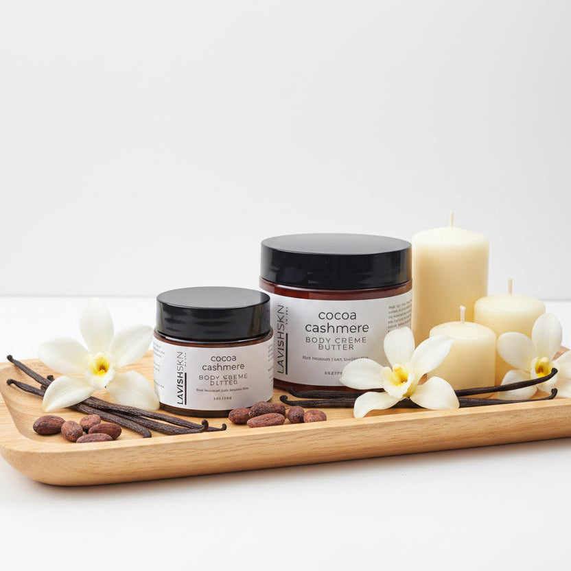 Two cosmetic jars of L Cocoa Cashmere Hand Cream Butter, one in a smaller black jar and one in a larger brown jar, sitting on a white countertop.